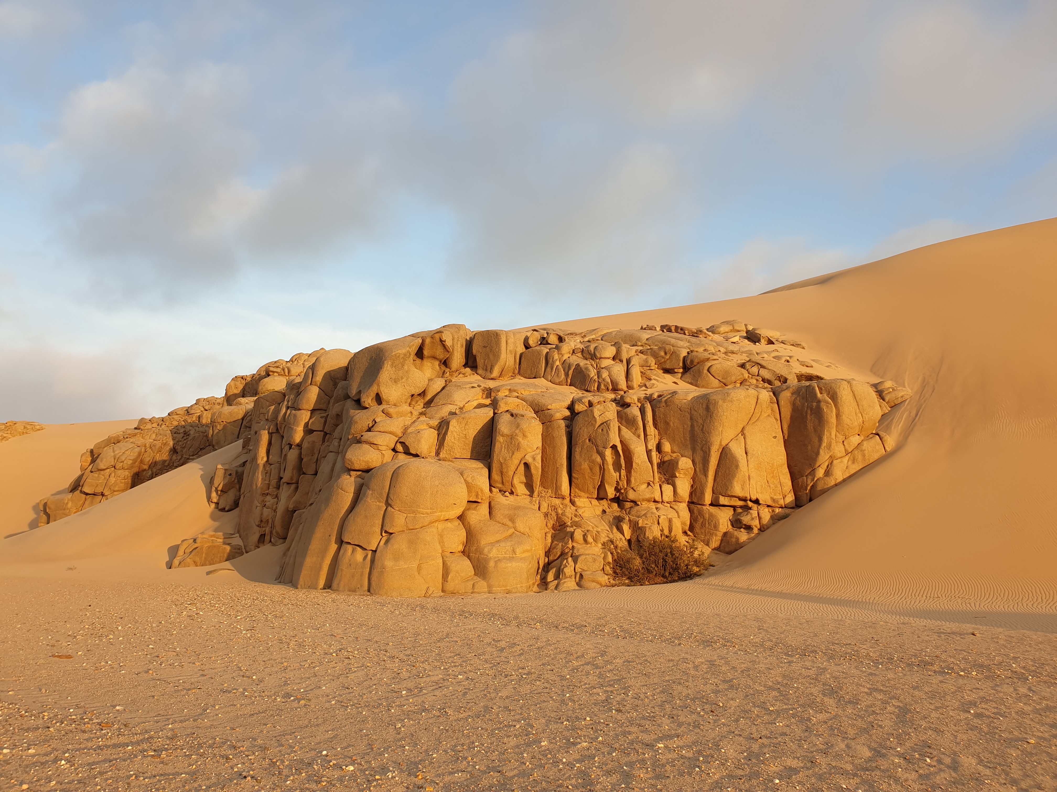 Masse rocheuse semblant "caler" la première dune  au bord de l'Océan atlantique, Shipwreck lodge, Côte des Squelettes, Namibie.